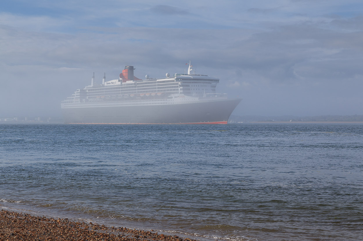 Queen Mary 2 emerges from fog on Southampton Water as she passes Calshot Castle.