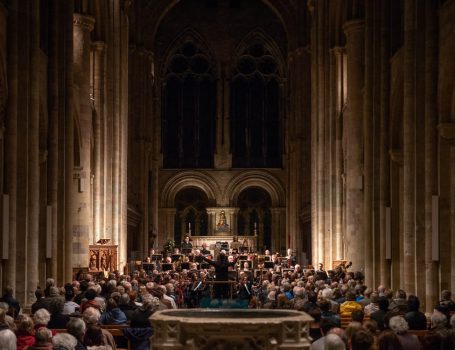 Wide-angle view of conductor and orchestra during musical climax of concert in large church